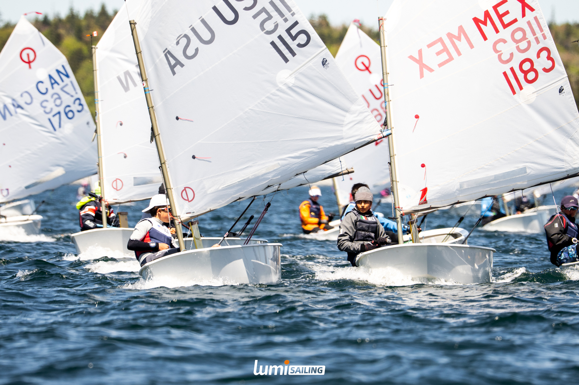 Optimist fleet racing tightly together in breeze and chop