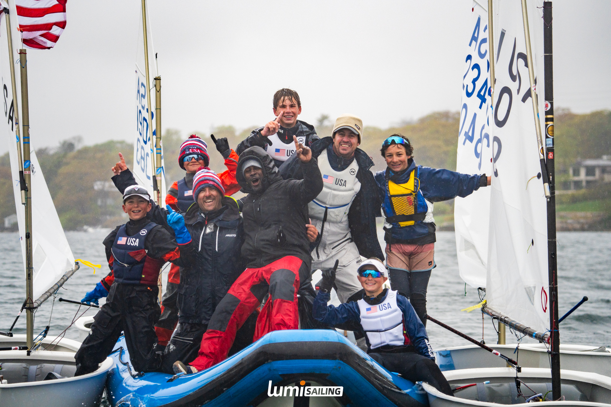 Youth sailing team celebrating together on the water after racing
