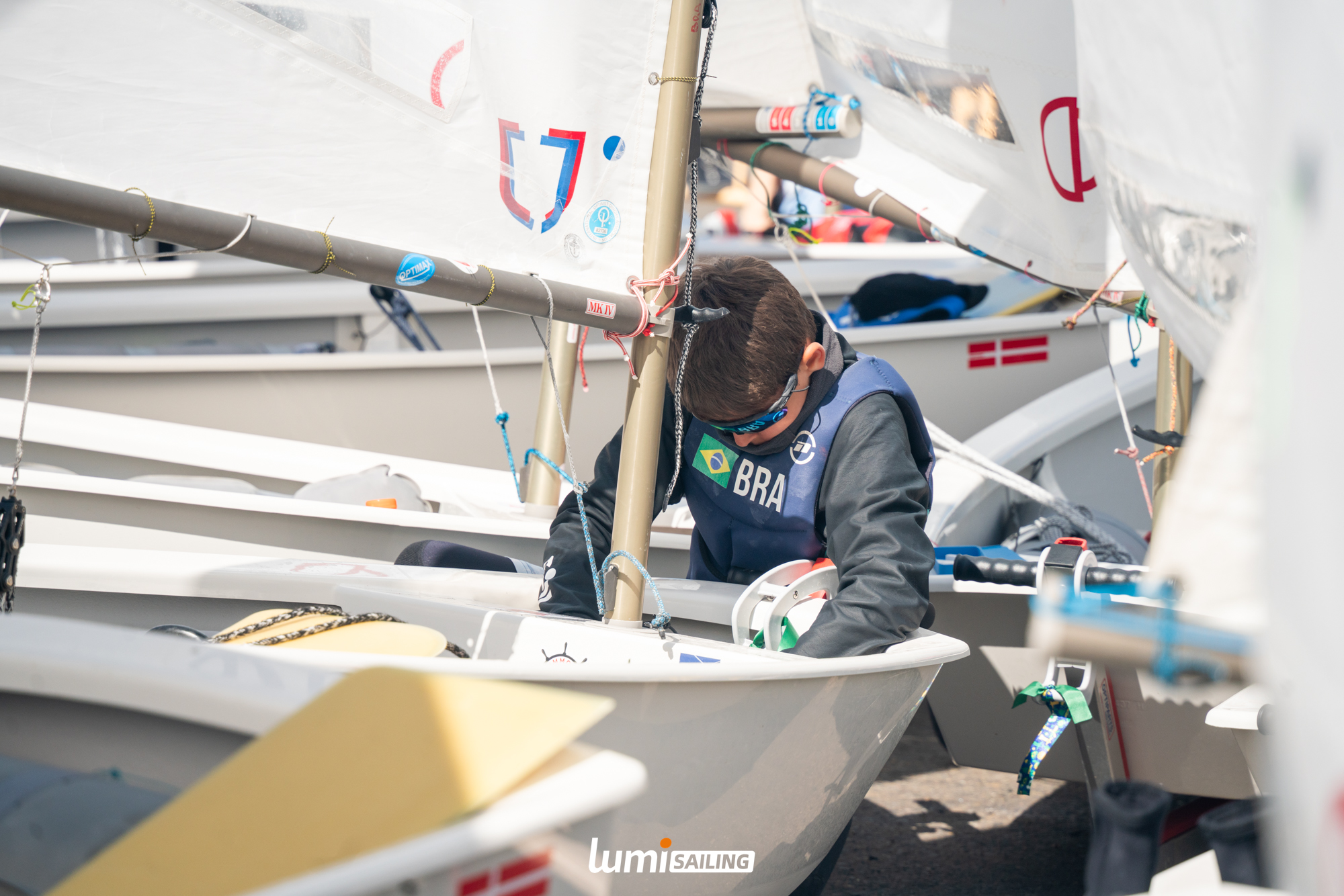 Young sailor preparing an Optimist dinghy before racing