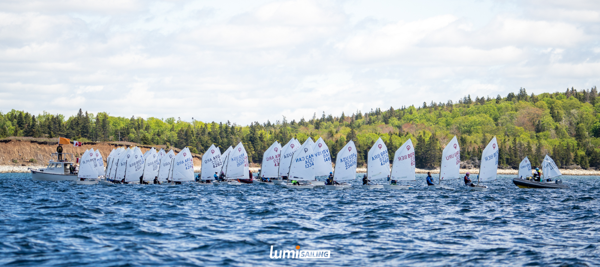 Wide view of an Optimist fleet lined up on the course
